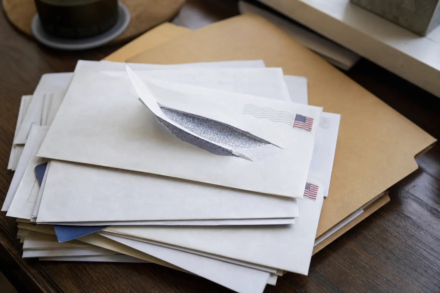 Stack of opened mail and a manila folder on a desk