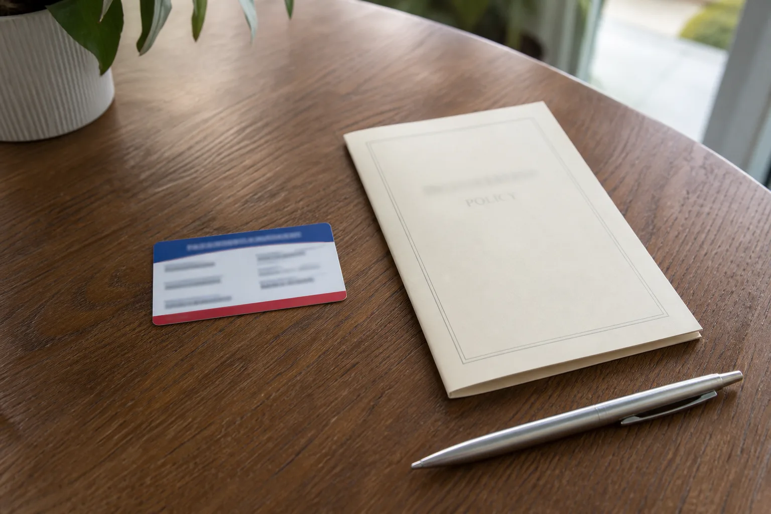Red-white-and-blue insurance card next to a cream policy booklet on a wood table